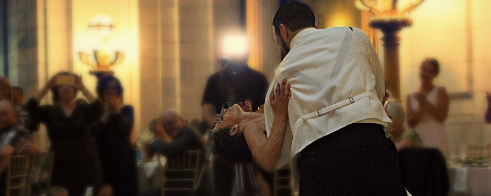 A first dance, the groom dipping the bride while the room watches